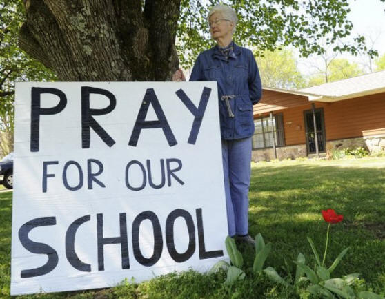 Lenoir City resident June Quillen, 82, shows off her yard sign Tuesday across the street from Lenoir City High School. Quillen said she made the sign to show support for students after the Lenoir City school board ceased opening its meetings with a prayer. (AMY SMOTHERMAN BURGESS/NEWS SENTINEL)

